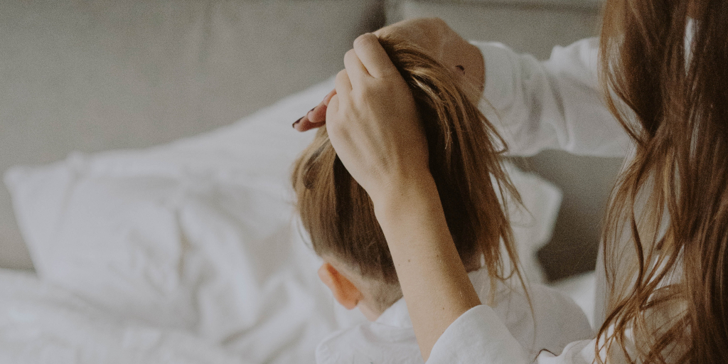 Past-Miranda. Photo by Mathilde Langevin on Unsplash. Shows a woman fixing her daughter's ponytail.