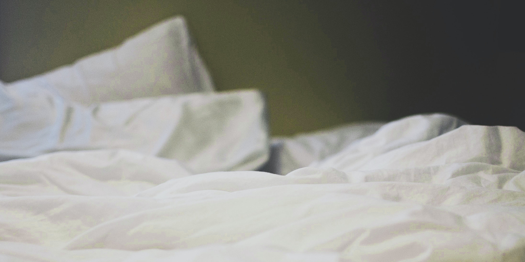Enlightened_Photo by Cassidy Dickens on Unsplash. Shows bed with rumpled white sheets.